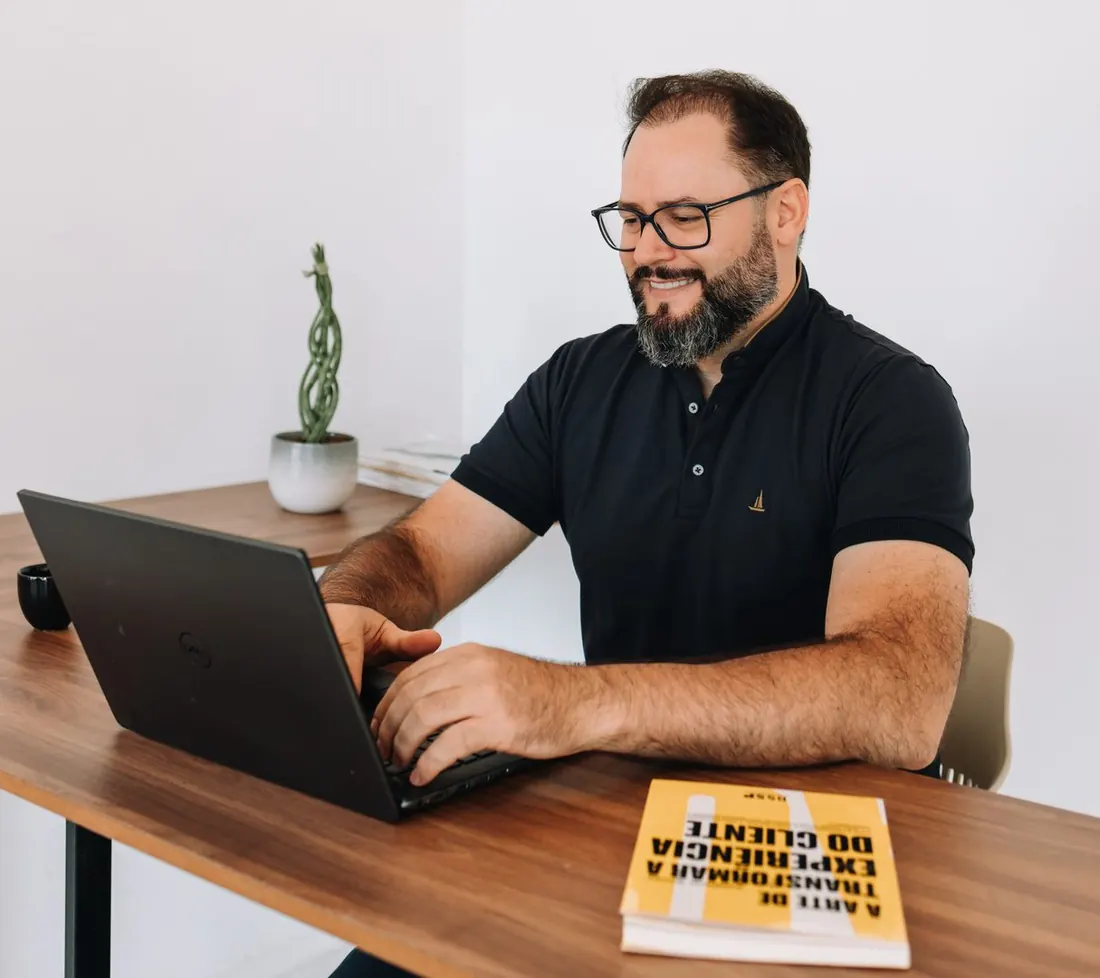 Valdimar Souza trabalhando à mesa, com o livro A Arte de Transformar a Experiência do Cliente ao lado